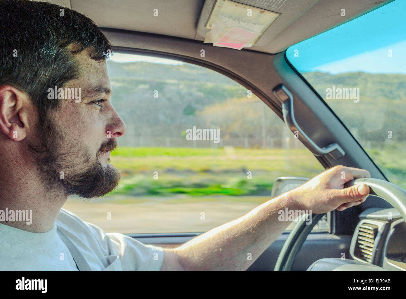 Uomo caucasico la guida auto sulla strada rurale Foto Stock