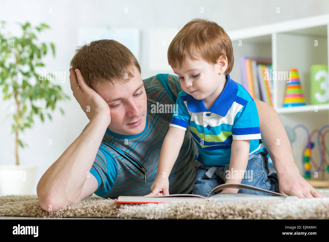 Kid boy e padre di leggere un libro sul pavimento per interni Foto Stock