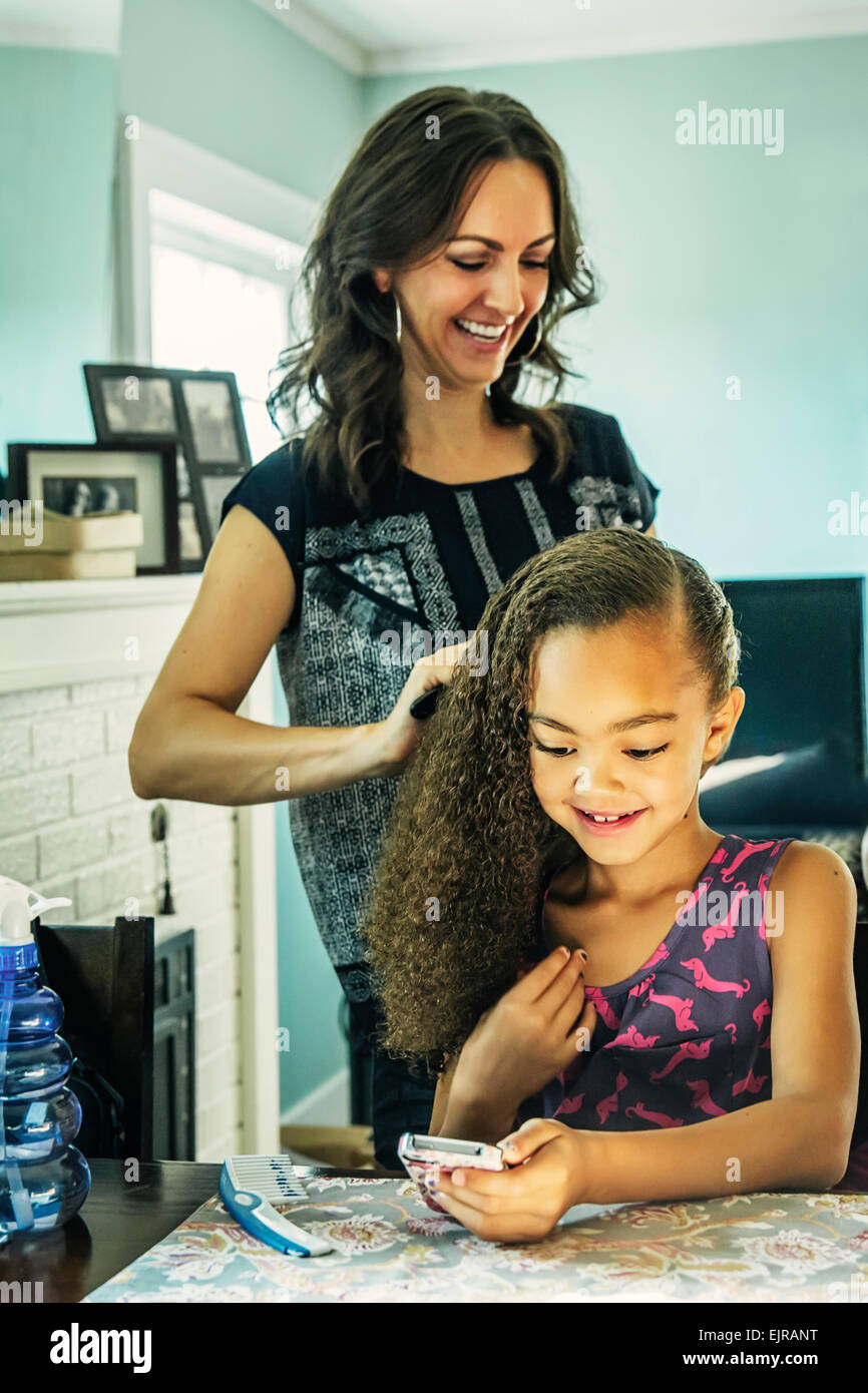 Madre sorridente spazzolare i capelli della figlia Foto Stock