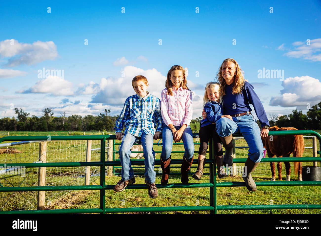 L'agricoltore caucasica e bambini seduti sul recinto sul ranch Foto Stock