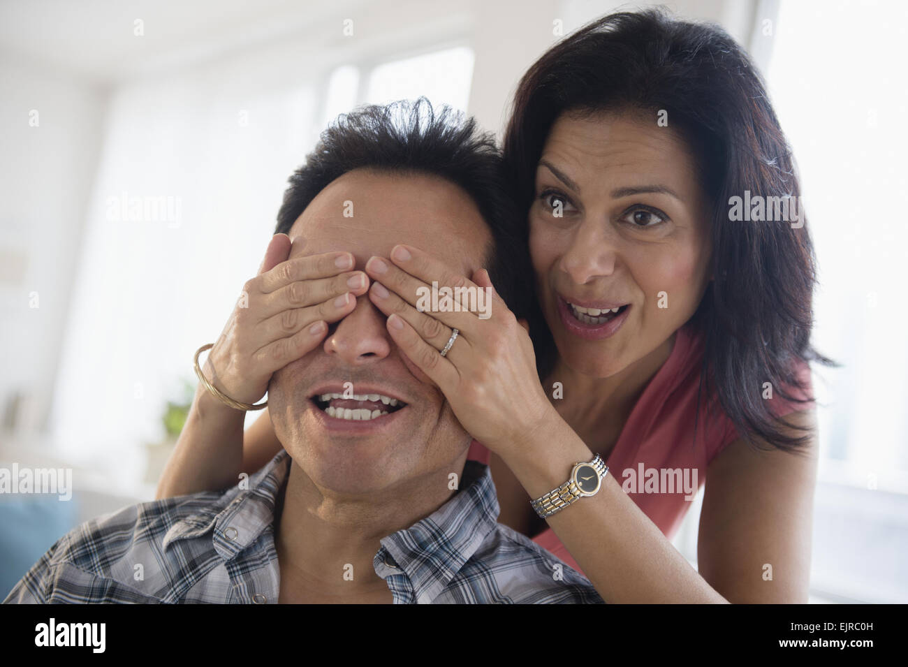 Donna che copre gli occhi del marito Foto Stock