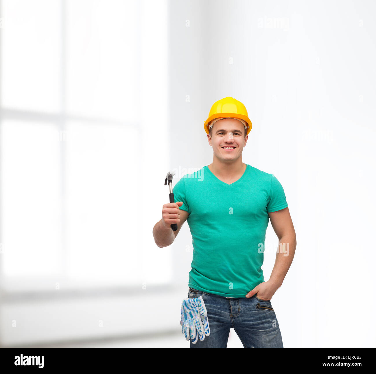 Sorridente lavoratore manuale nel casco con martello Foto Stock