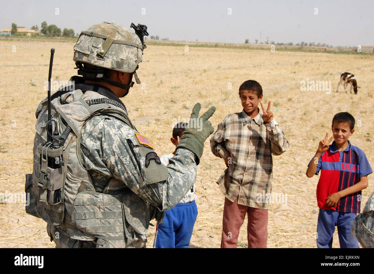 Sgt. 1. Classe Ernest Oberst, Gladstone, Mich, nativo, insegna ai bambini iracheni come fare il segno di pace durante il funzionamento un martello Bonzai XI in Taji Qada, a nord-ovest di Baghdad. Oberst serve come un plotone fanteria sergente in Azienda B, 52nd Reggimento di Fanteria, 1° Battaglione, 27 Reggimento di Fanteria "Wolfhound", 2° Stryker Brigade Combat Team "guerriero", XXV divisione di fanteria, Divisione multinazionale - Bagdad. Foto Stock