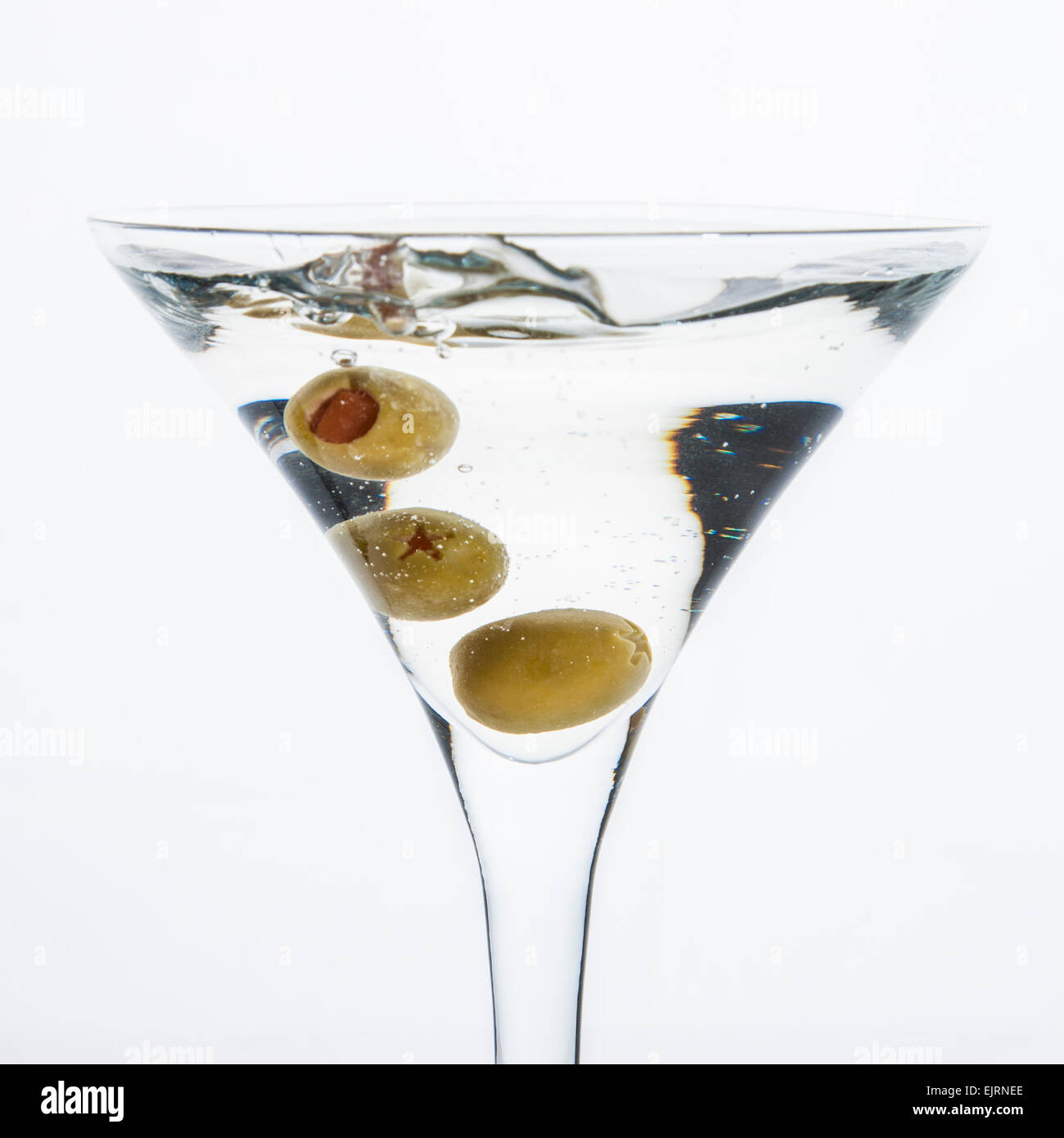 Un martini vetro su uno sfondo bianco; l'acqua increspature e schizzato come un verde oliva spagnolo con pimento è caduto nel Foto Stock