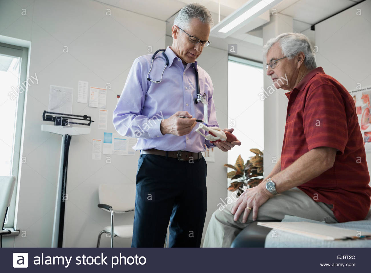 Medico mostrando senior ginocchio uomo modello di osso Foto Stock