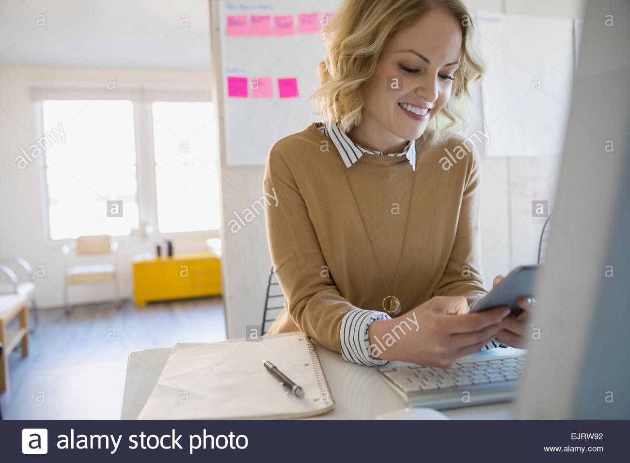 Imprenditrice sorridente alla messaggistica di testo in sala conferenze Foto Stock