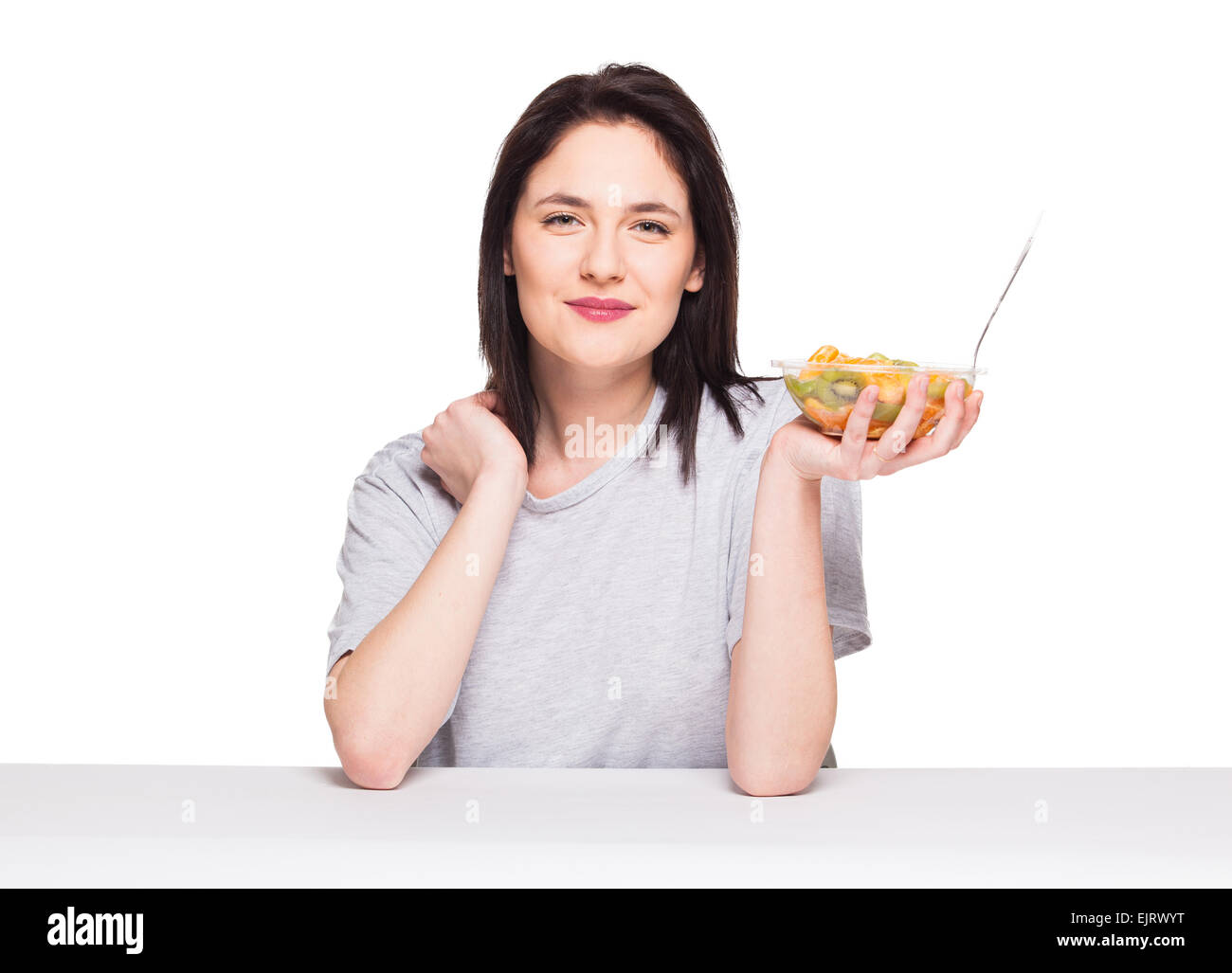 Bella donna sorridente e ansante un sani frutti pasto con arancia e kiwi, isolato su bianco Foto Stock