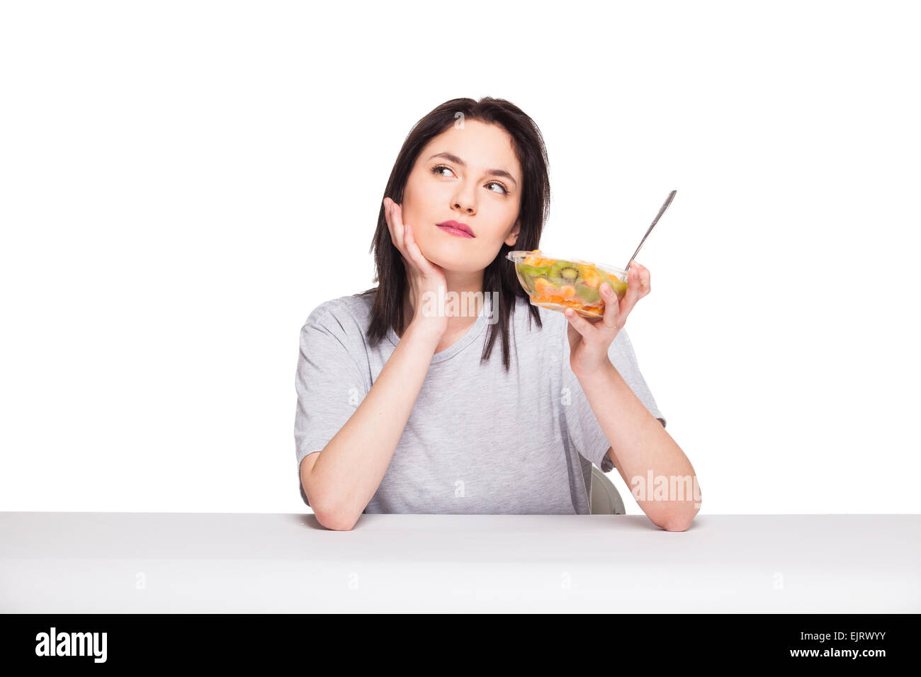 Giovane donna naturale cercando annoiato e pensando al suo pasto sano, isolato su bianco Foto Stock