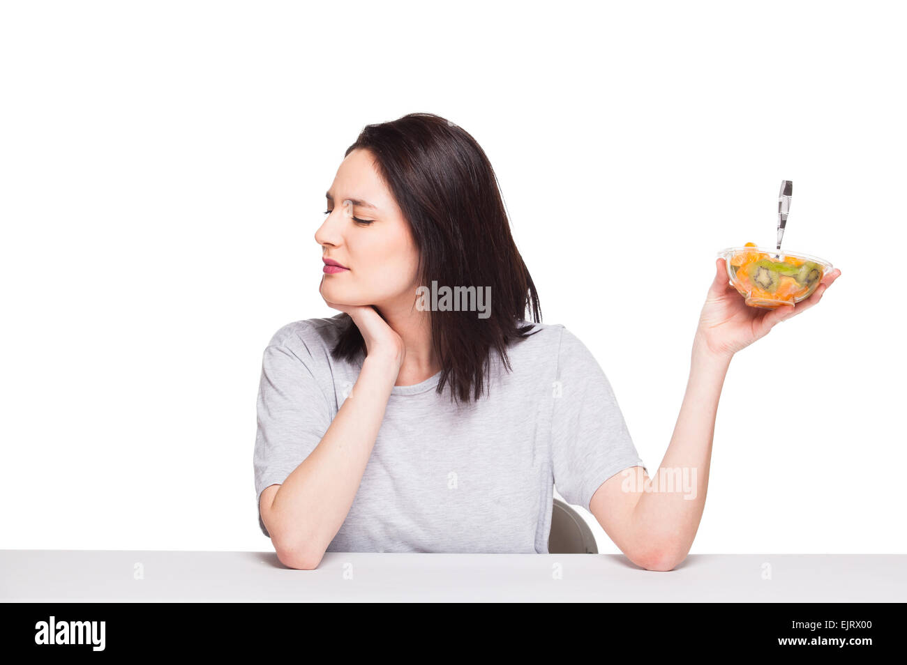 Giovane donna naturale rifiutando il cibo sano con arancia e kiwi, isolato su bianco Foto Stock