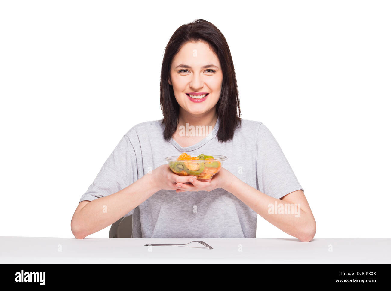 Bella donna sorridente e ansante un sani frutti pasto con arancia e kiwi, isolato su bianco Foto Stock