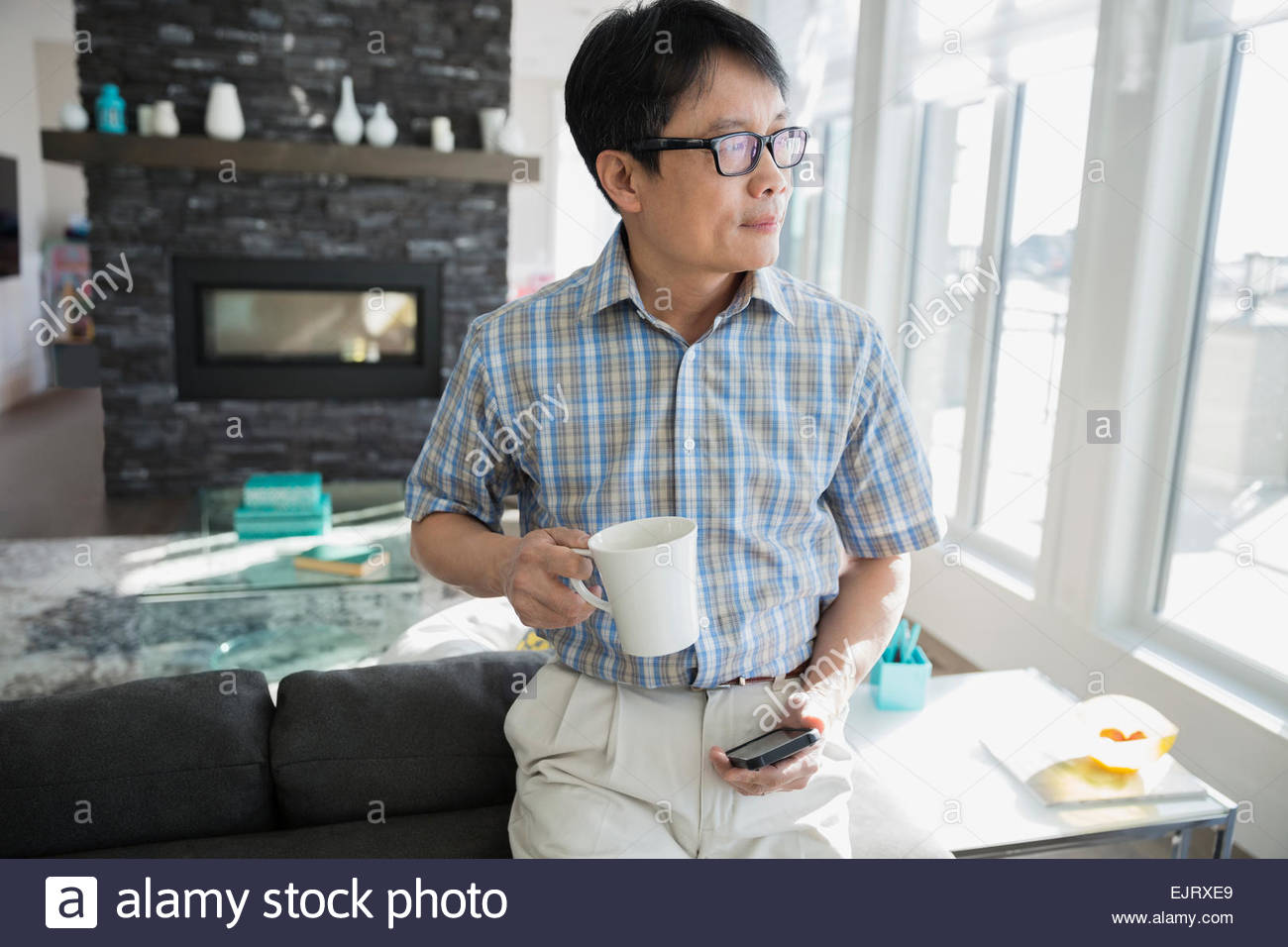 Uomo con caffè e telefono cellulare che guarda lontano Foto Stock