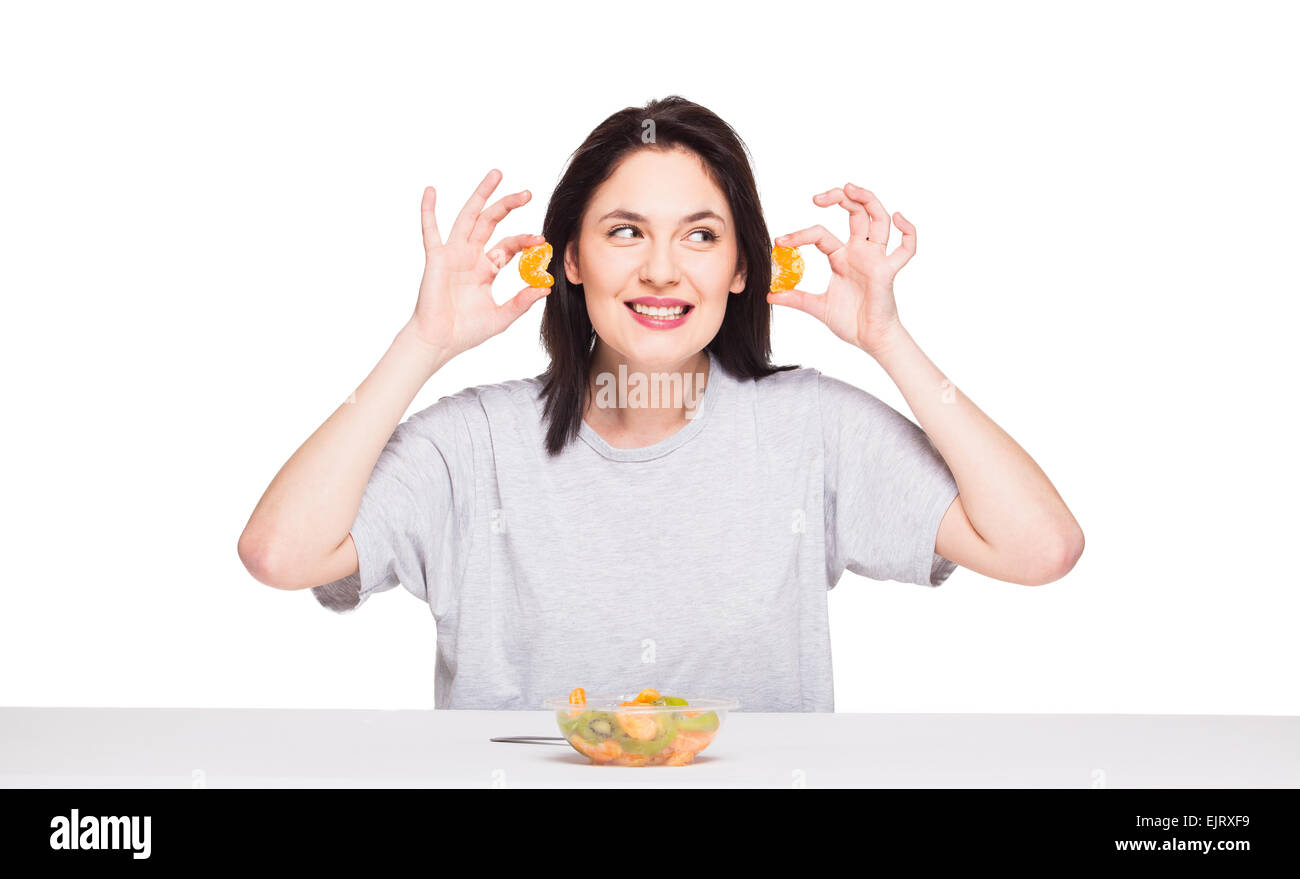 Giovani espressiva naturale donna che gioca con il suo cibo sano, arancio e kiwi, isolato su bianco Foto Stock