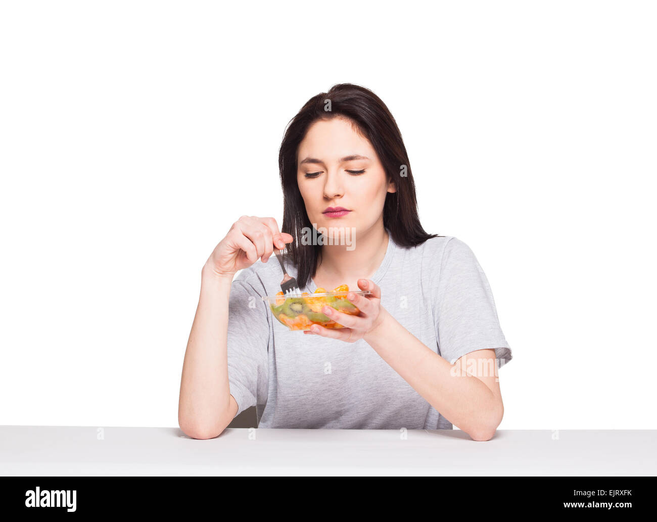 Giovane donna naturale cercando annoiato e pensando al suo pasto sano, isolato su bianco Foto Stock