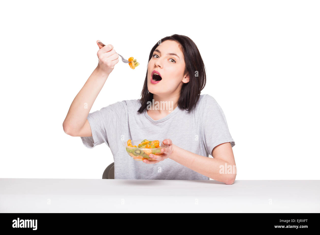 Donna naturale di mangiare cibo sano con arancia e kiwi su sfondo bianco Foto Stock