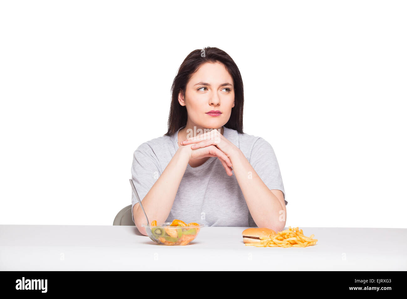Immagine di donna con frutta e hamburger nella parte anteriore su sfondo bianco, sano versus junk food concept Foto Stock