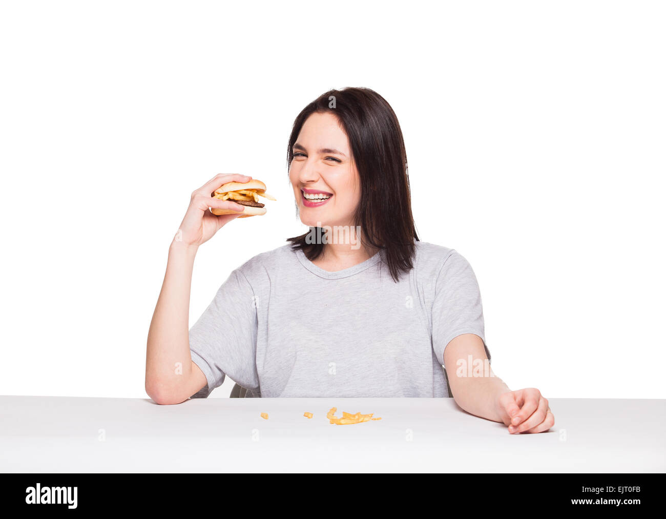 Giovane donna naturale di mangiare cibo spazzatura, hamburger e patatine fritte, su sfondo bianco Foto Stock