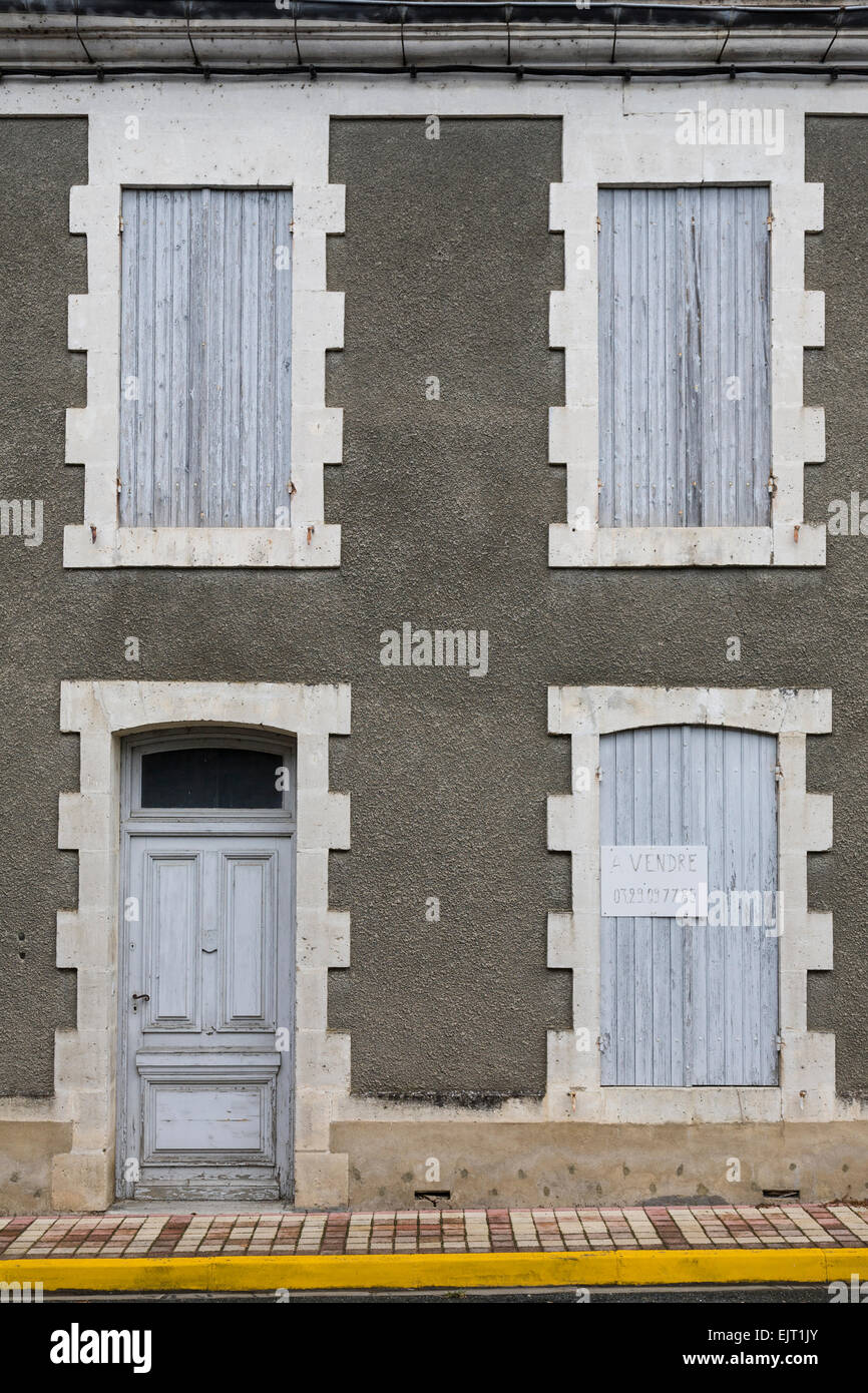 Facciata di una casa francese con chiusura verniciato grigio di persiane alle finestre e un 'A Vendre' (in vendita) segno esposto. Foto Stock