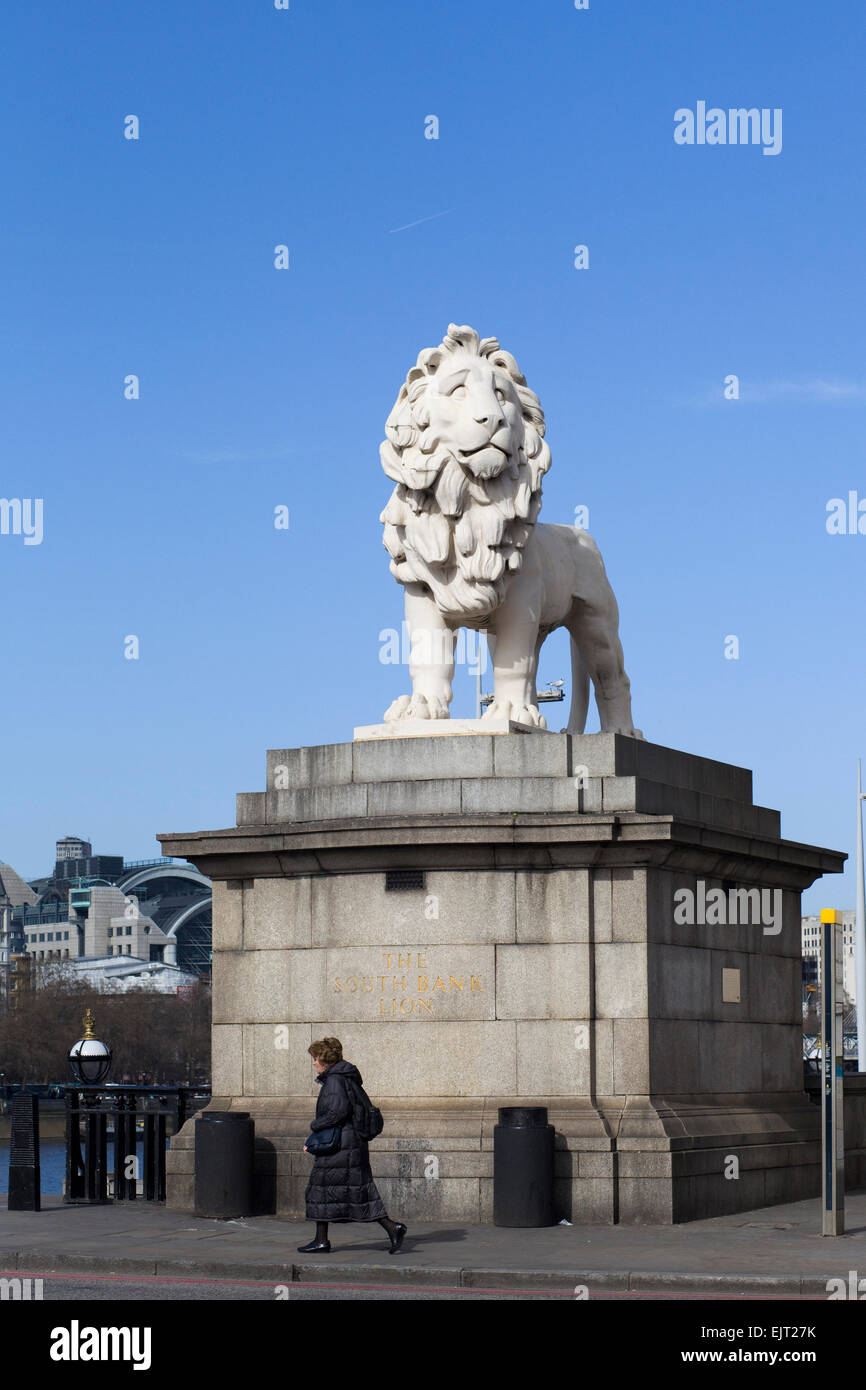 La donna a camminare lungo la famosa La Coade leone di pietra a guardia della estremità meridionale del Westminster Bridge Foto Stock