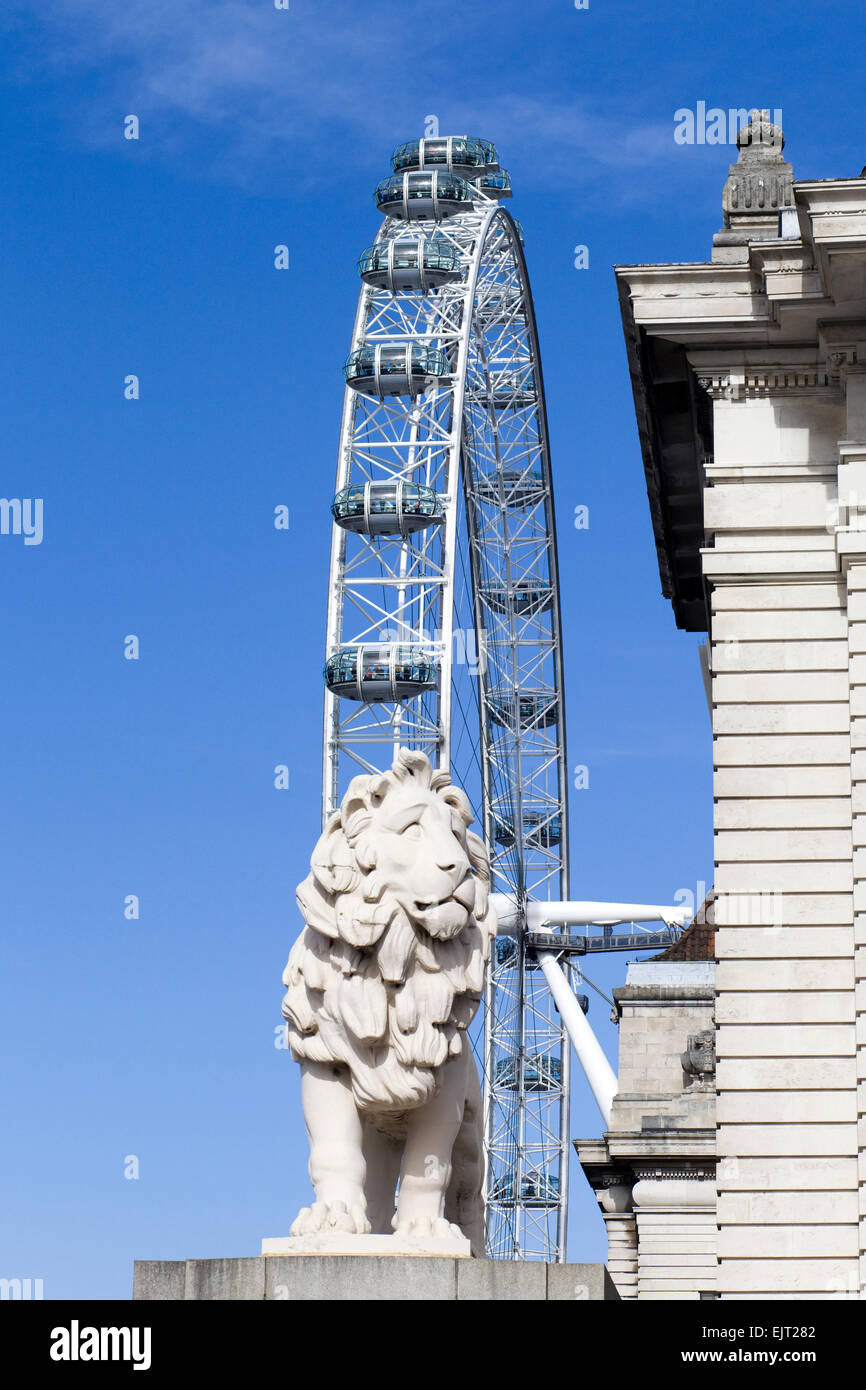 La Coade leone di pietra a guardia della estremità meridionale del Westminster Bridge con il London Eye sullo sfondo Inghilterra Foto Stock