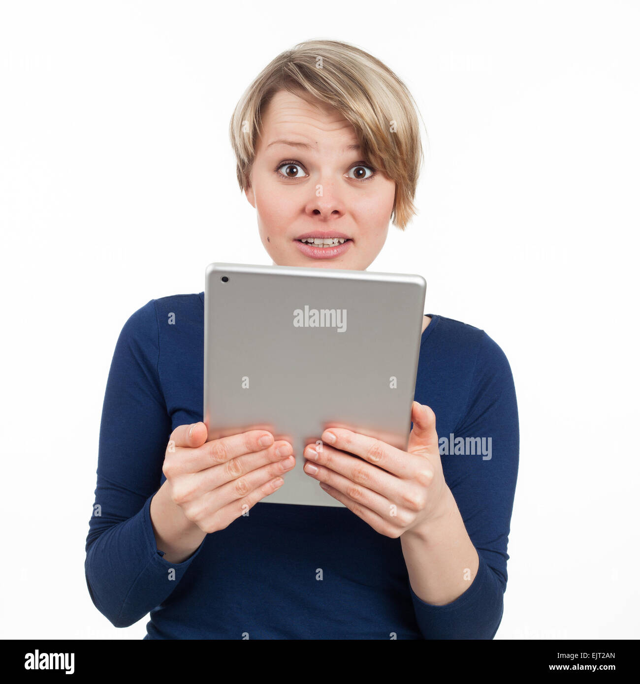 Giovane donna tenendo una tavoletta elettronica e guardando disturbato, isolato su bianco Foto Stock