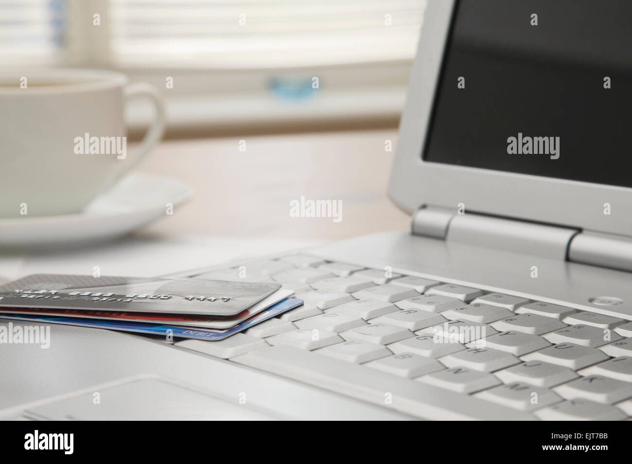 Vicino la banca e le carte di credito su un computer portatile con una tazza di caffè caldo in background Foto Stock