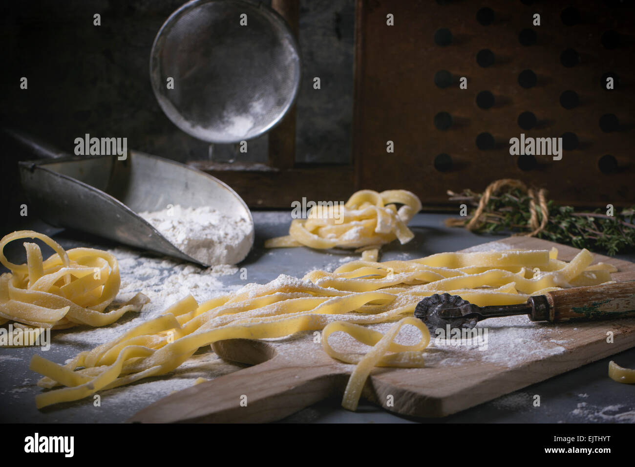 Rendendo la pasta fatta in casa linguine rustico tavolo da cucina con farina, vintage crivello e tagliere. Vedere serie. Foto Stock