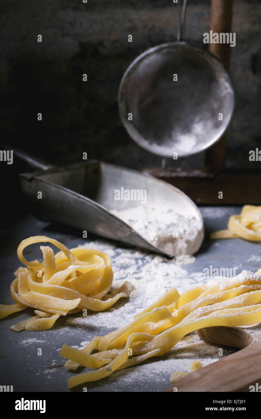Rendendo la pasta fatta in casa linguine rustico tavolo da cucina con farina, vintage crivello e tagliere. Vedere serie. Foto Stock
