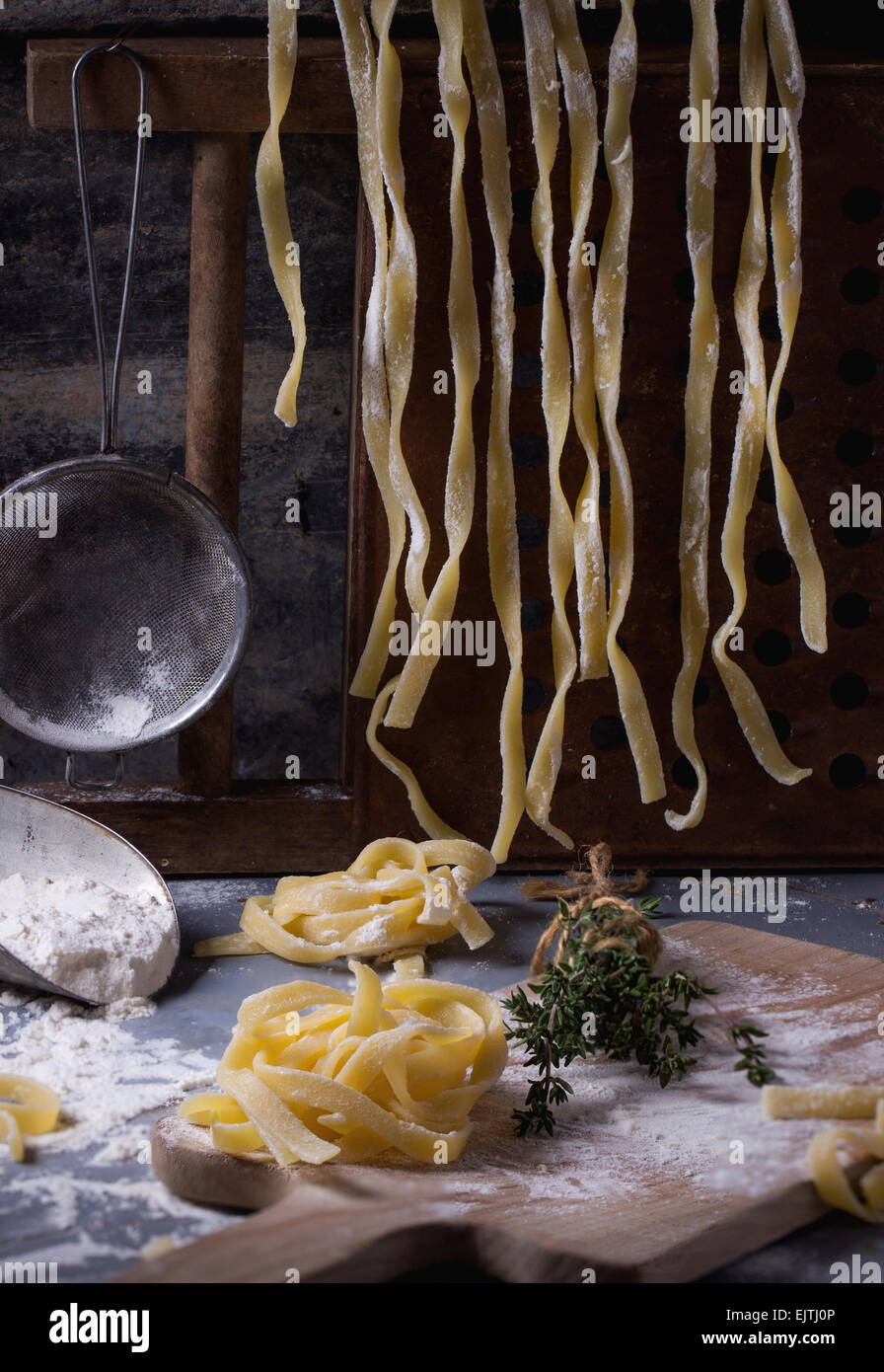 Rendendo la pasta fatta in casa linguine rustico tavolo da cucina con farina, vintage crivello e tagliere. Vedere serie Foto Stock