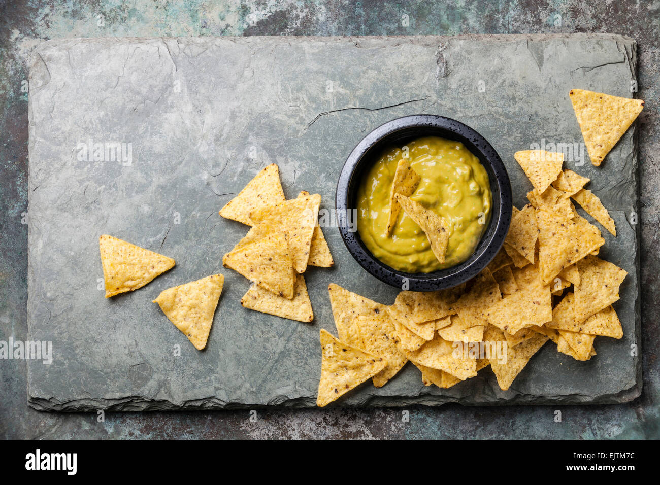 Guacamole fresco dip con nachos chips su pietra sullo sfondo di ardesia Foto Stock