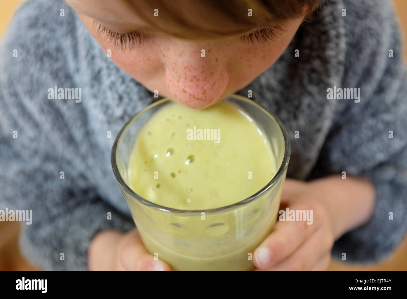 Un ragazzo bere un succo verde smoothie per colazione fatta da avocado, mela, banana e ananas Foto Stock