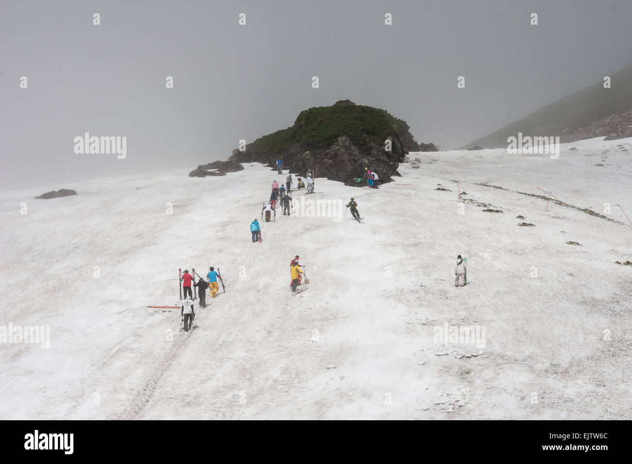 Gli sciatori estate camminate fino a un campo di neve a monte Norikura su un nuvoloso giorno di luglio, Nagano, Giappone Foto Stock