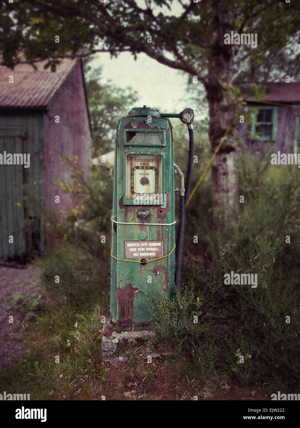 Un vecchio arrugginito, vendemmia verde pompa benzina in un abbandonati, malandato garage in campagna. Foto Stock