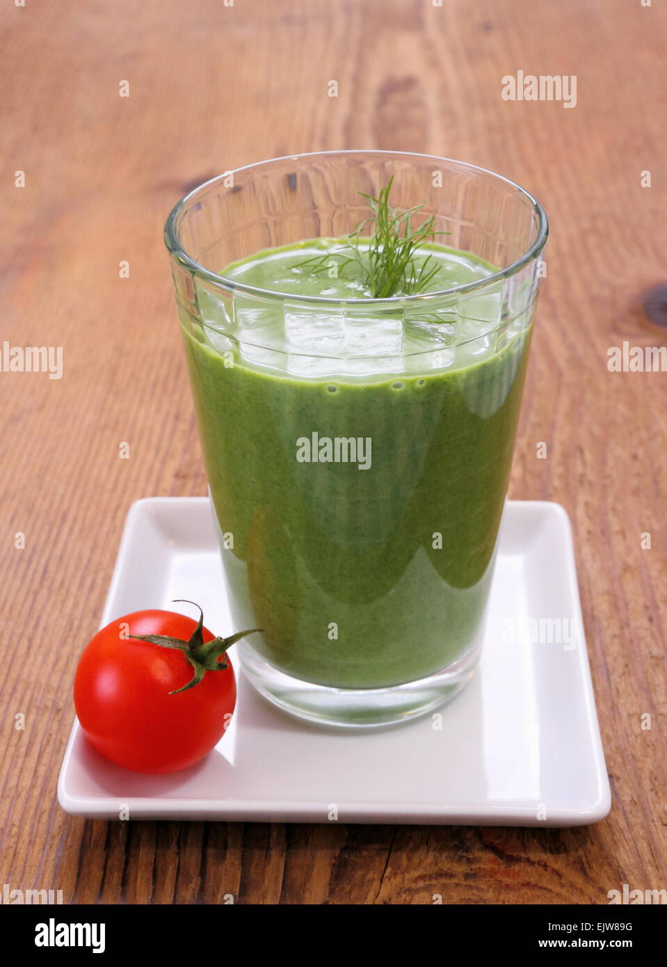 Verde frullato di spinaci con piccolo rosso pomodoro, close up Foto Stock