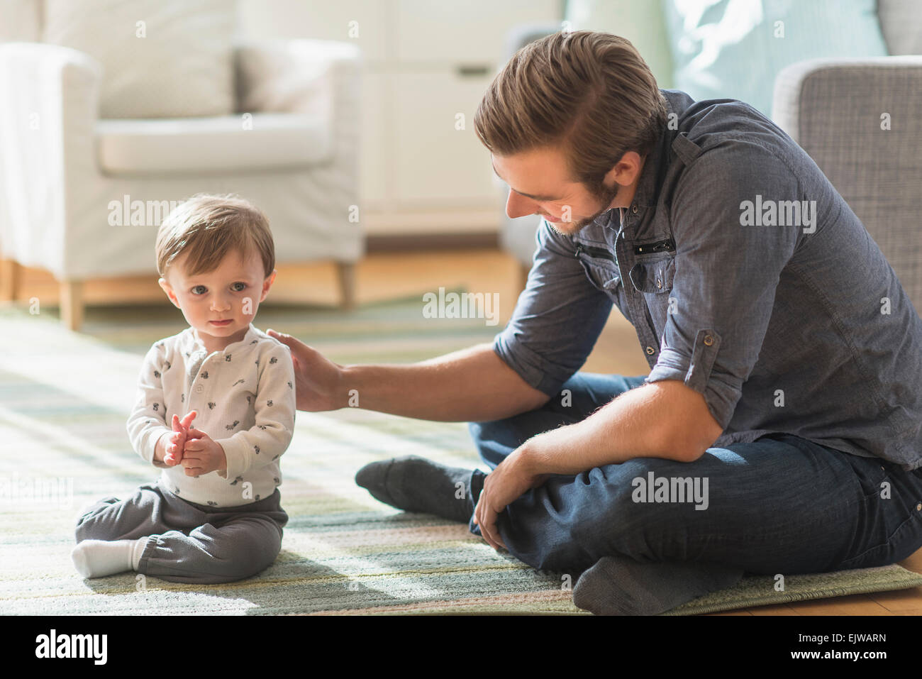 Padre seduto sul pavimento con piccolo figlio (2-3 anni) Foto Stock