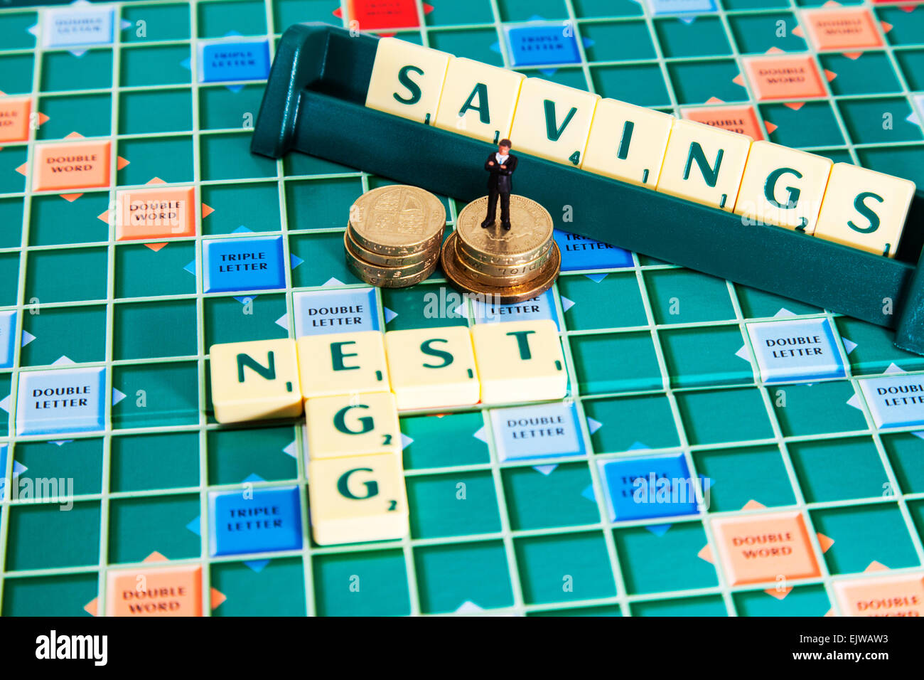 Uovo di nido risparmi soldi pound monete pension salvare Rainy day parole fondo usando piastrelle scrabble per illustrare l'ortografia compitare Foto Stock