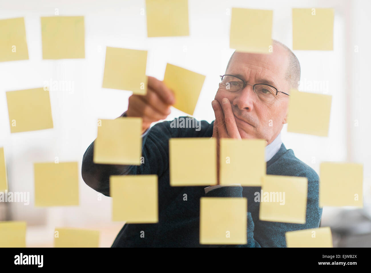 Imprenditore disponendo note adesive sulla parete di vetro Foto Stock