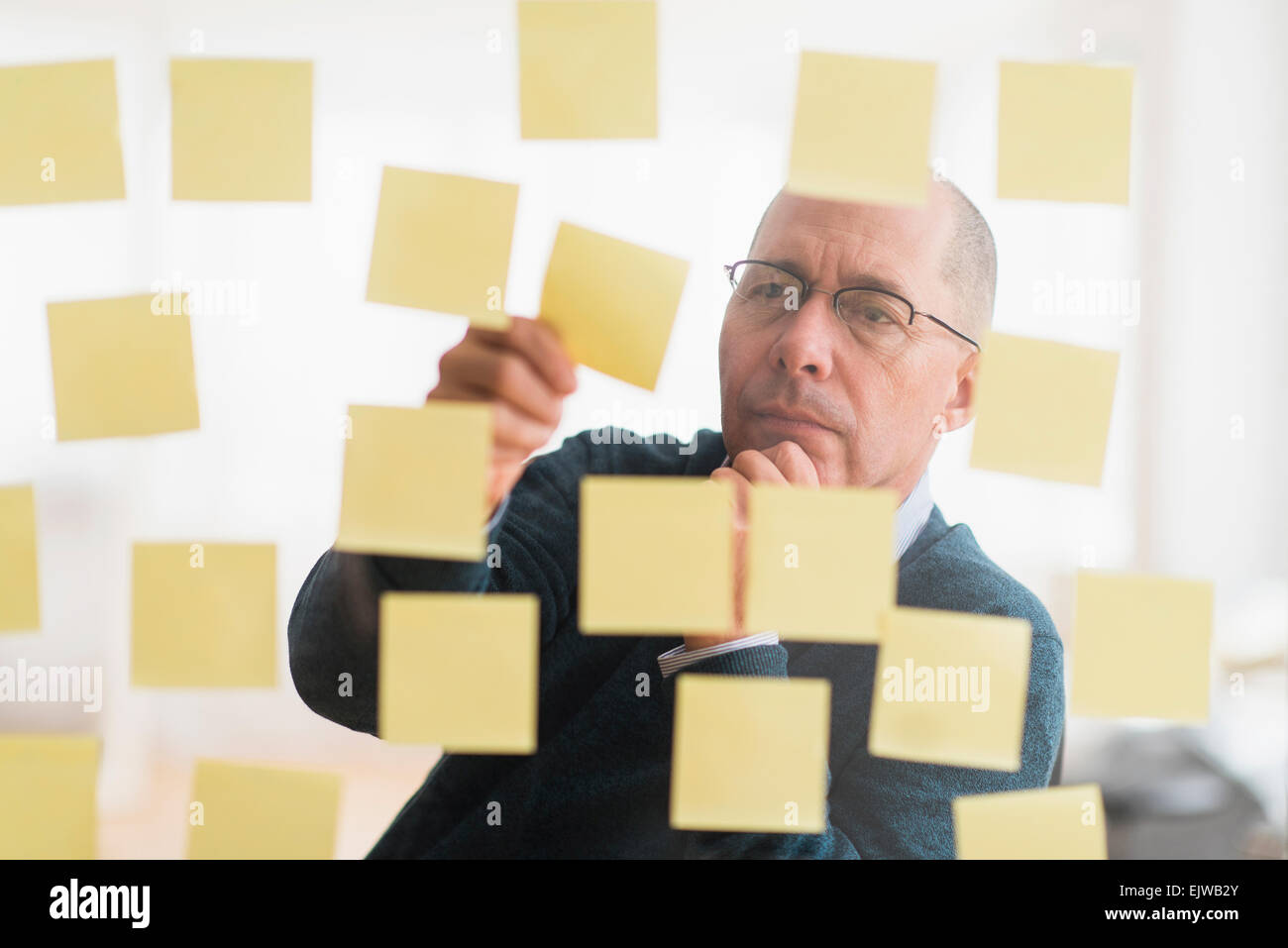 Imprenditore disponendo note adesive sulla parete di vetro Foto Stock