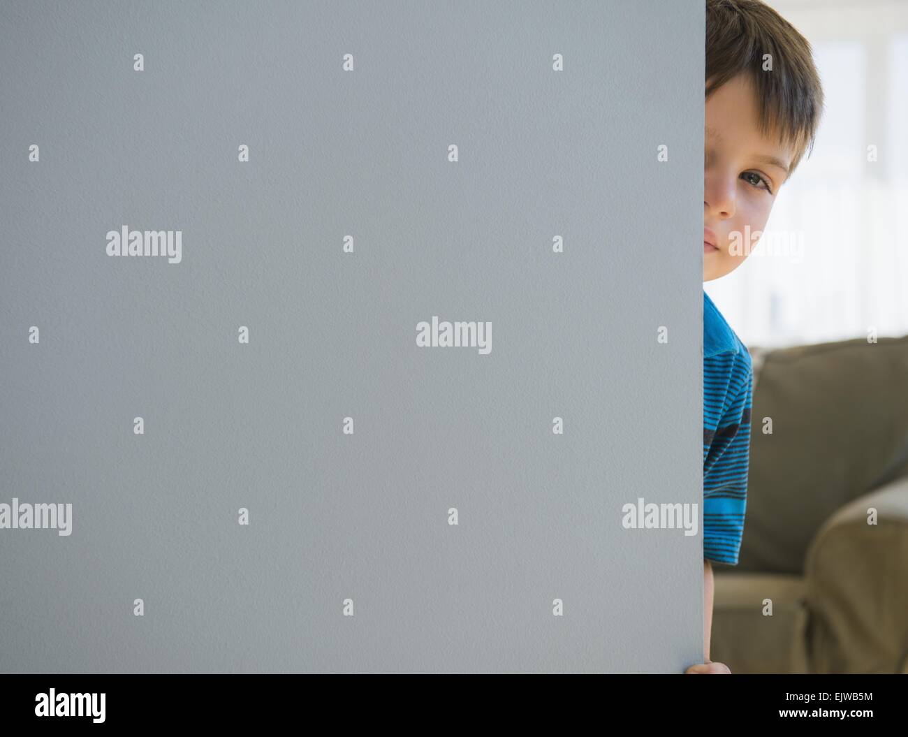 Ragazzo (6-7) Il peering attorno allo sportello Foto Stock