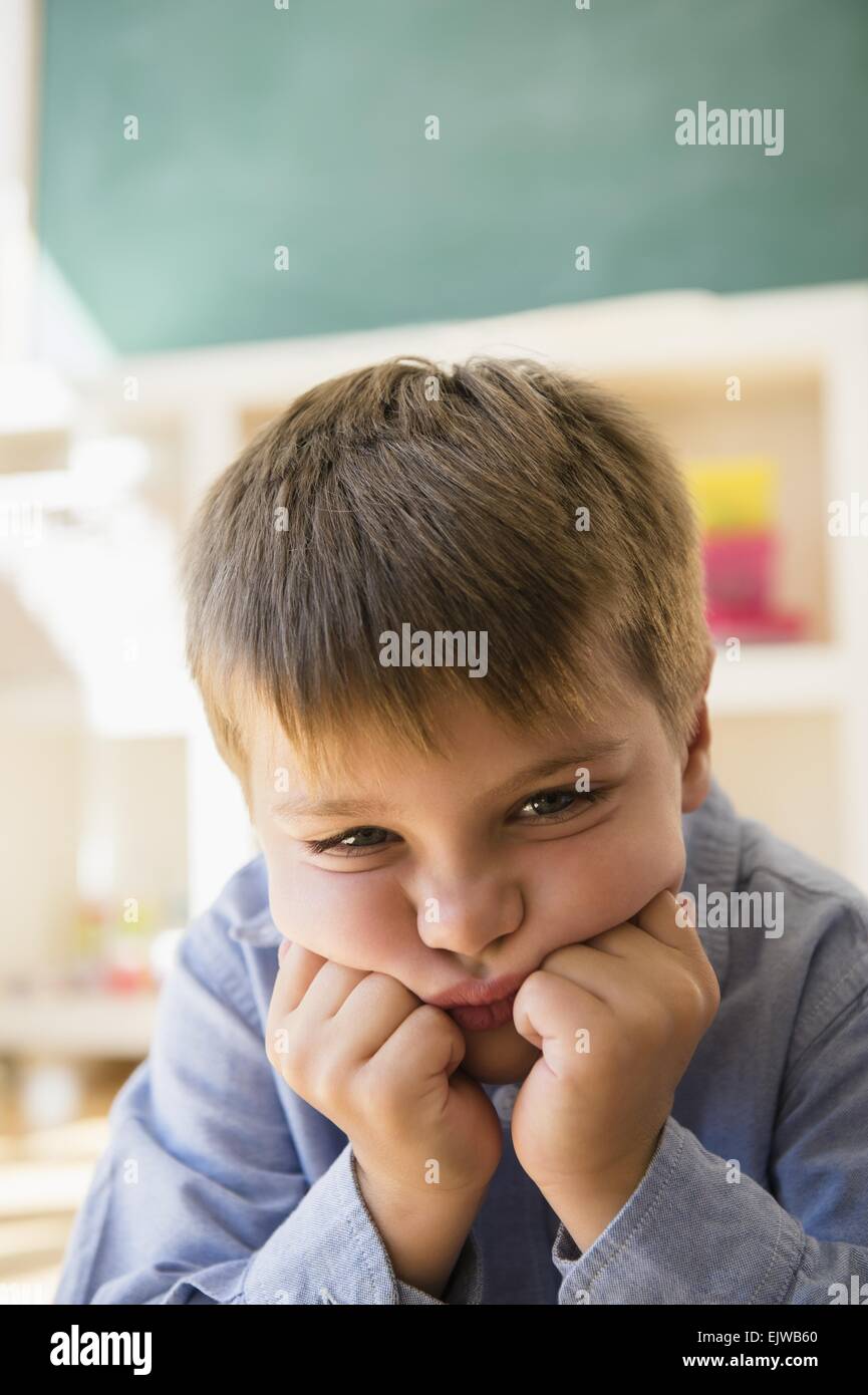 Ritratto di frustrati ragazzo (6-7) seduta in aula Foto Stock