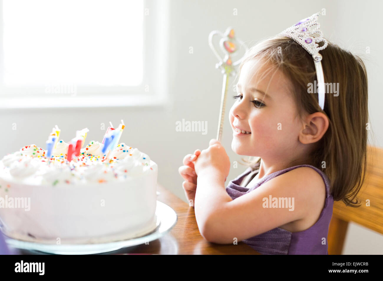 La ragazza (4-5) guardando alla torta di compleanno Foto Stock
