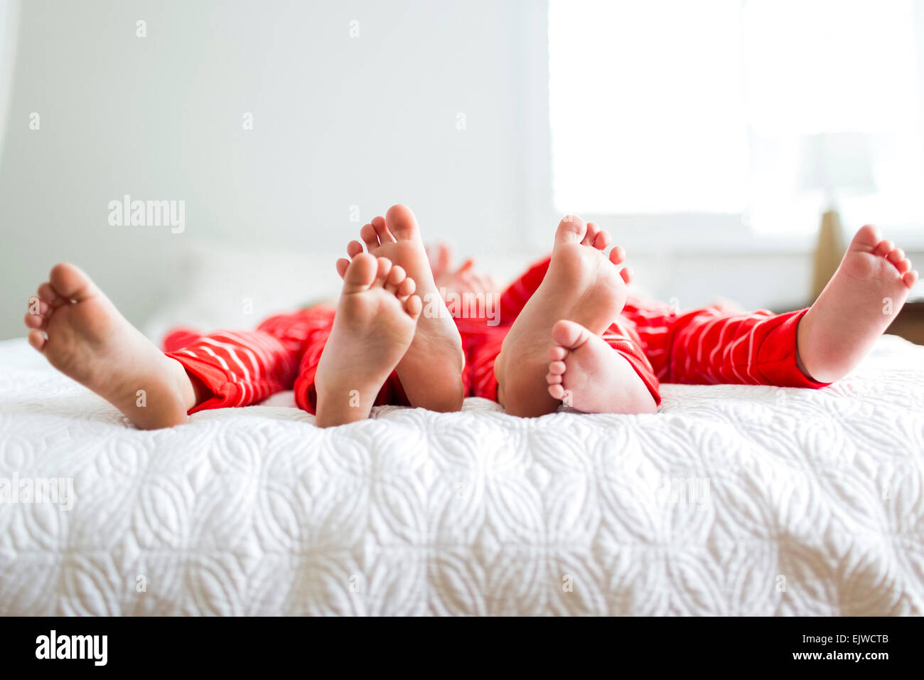 I fratelli (2-3, 4-5) in rosso pigiami giacente sul letto Foto Stock