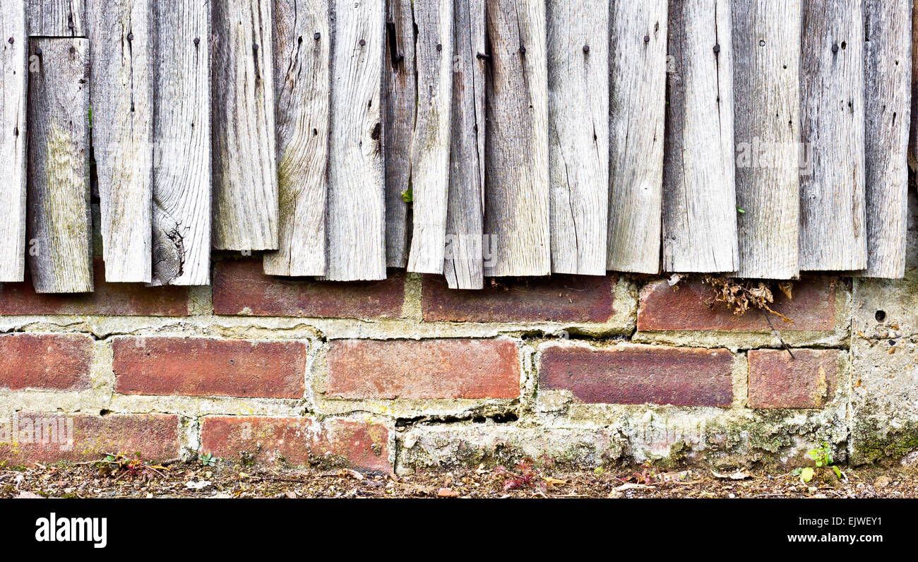 Weathered pannelli di recinzione contro un muro di mattoni Foto Stock