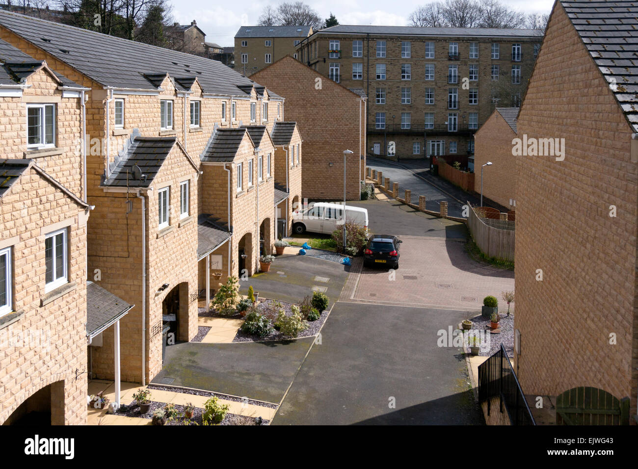 Moderne case in pietra con ex mulino in background, Sowerby Bridge, West Yorkshire Foto Stock