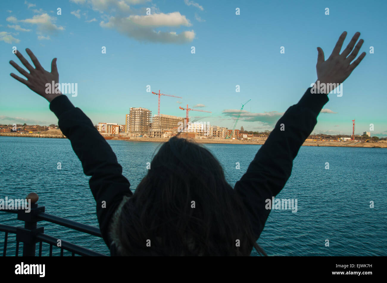 Una giovane donna con le braccia alzate in Ocean villagen Southampton Inghilterra. Una Mujer con los brazos en alto en Southampton Foto Stock