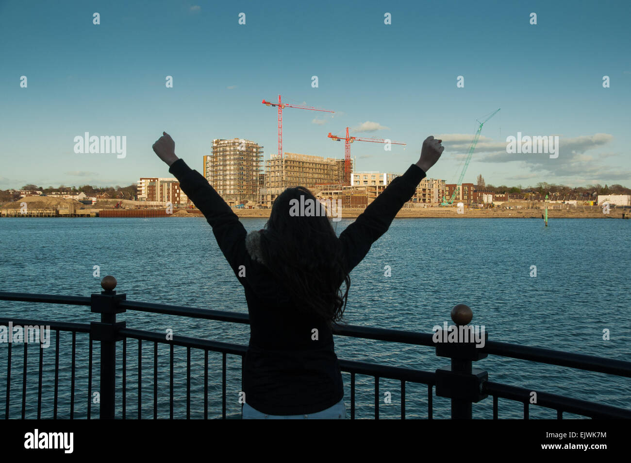 Una giovane donna con le braccia alzate in Ocean villagen Southampton Inghilterra. Una Mujer con los brazos en alto en Southampton Foto Stock