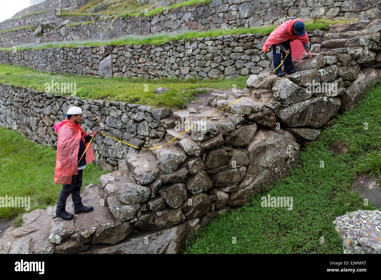 Il Perù, Machu Picchu. La conservazione storica. Misurazione dei lavoratori in connessione con la conservazione lavori in corso. Foto Stock
