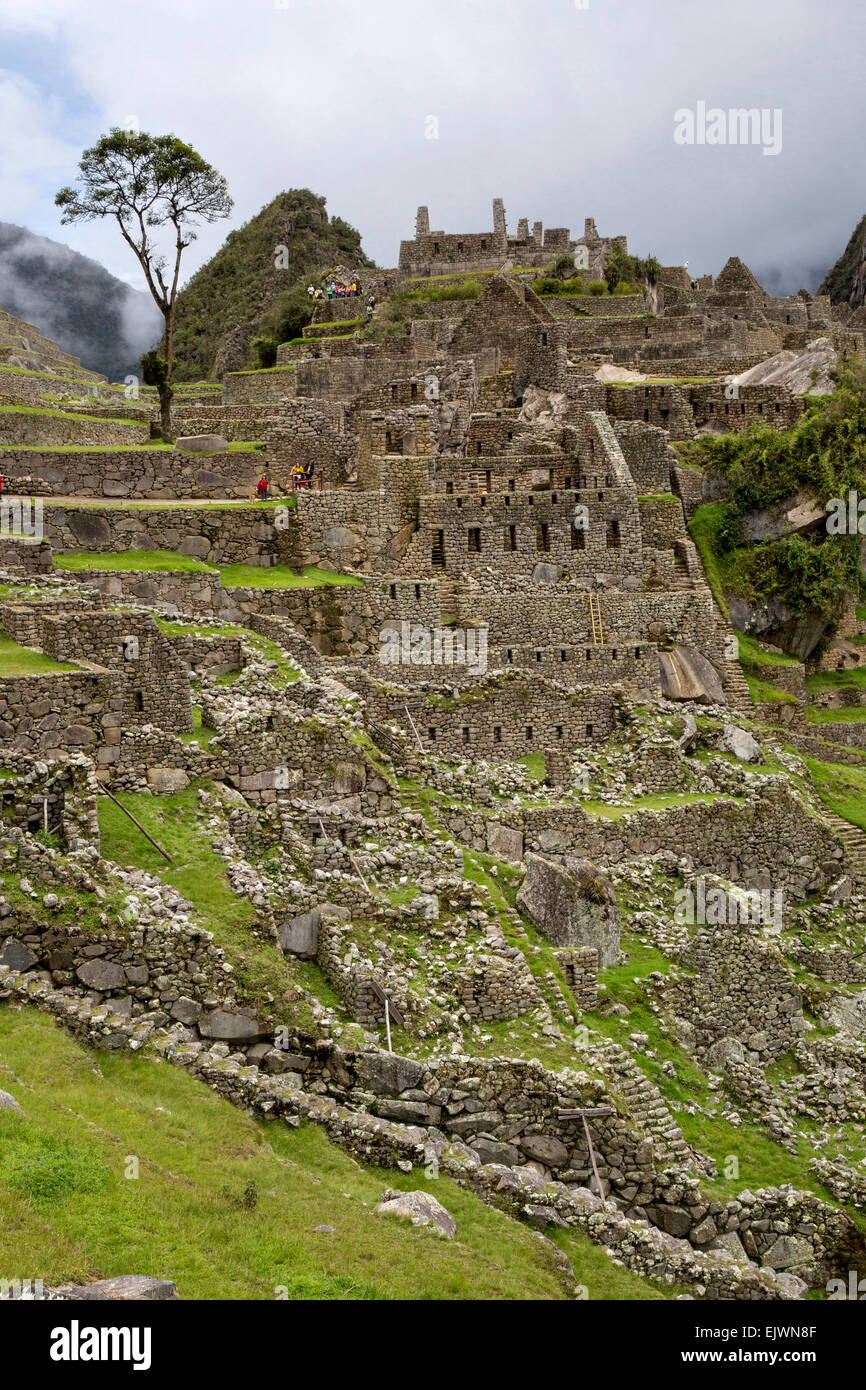 Il Perù, Machu Picchu, resti di case in Western settore urbano. I turisti in cima. Foto Stock