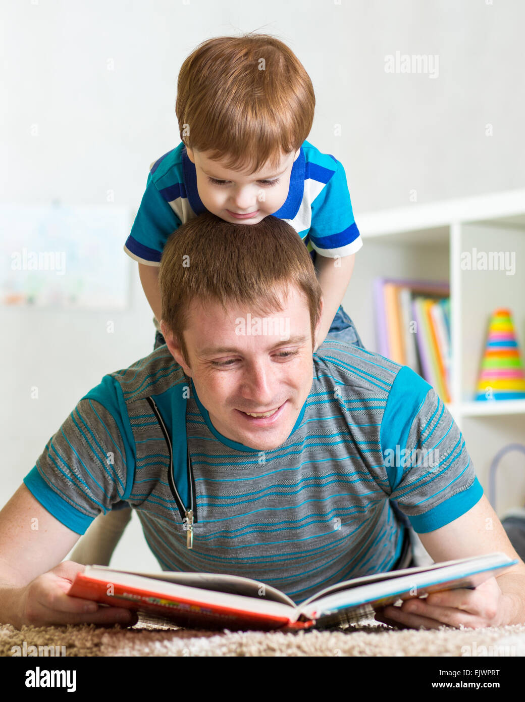 Bambino ragazzo e padre di leggere un libro sul pavimento a casa Foto Stock