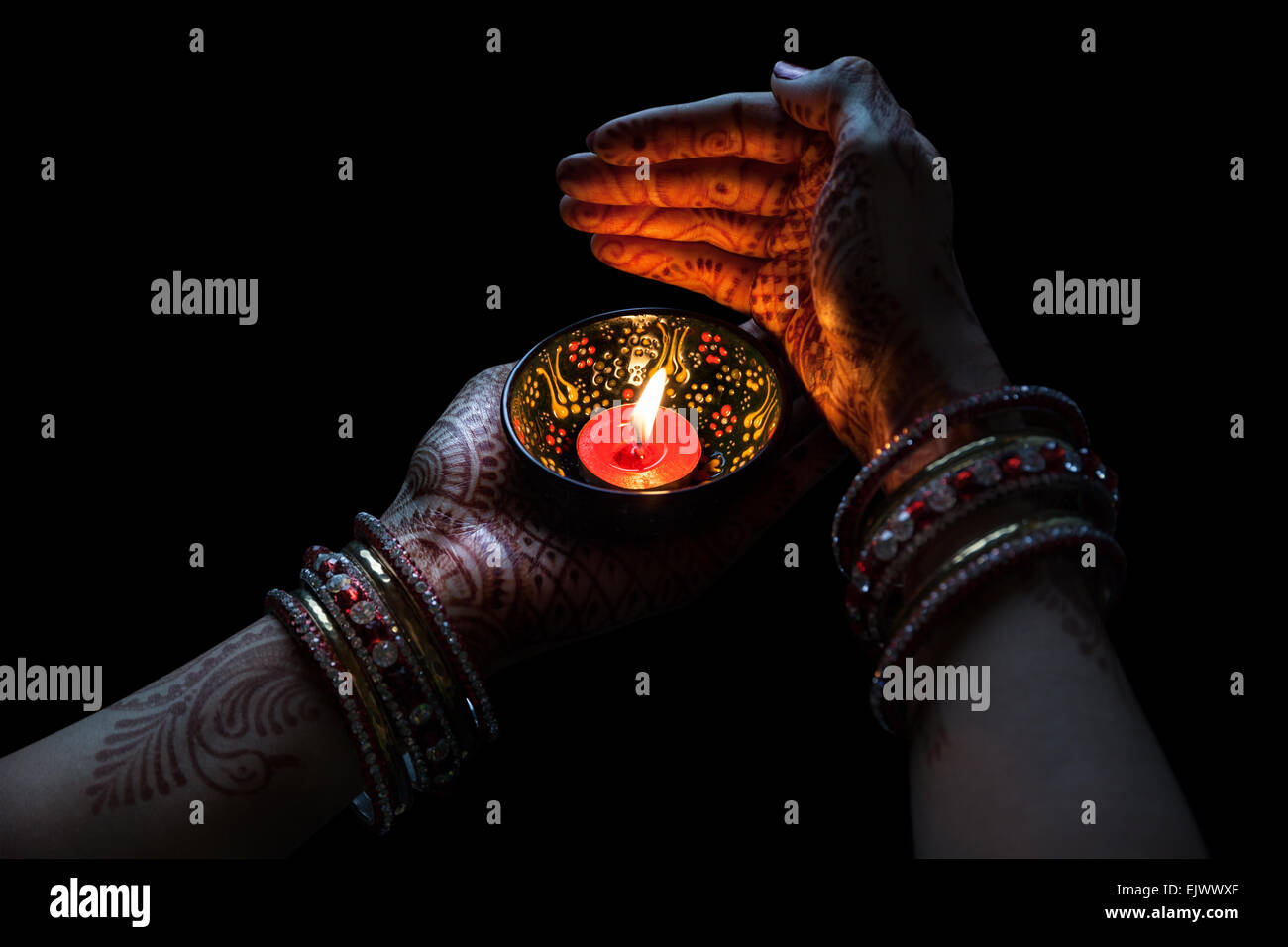 Donna mani con henna holding candela isolata su sfondo nero con tracciato di ritaglio Foto Stock