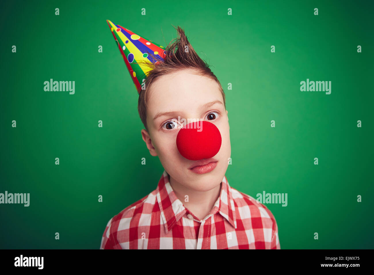 Ragazzo carino con cappuccio di compleanno e naso rosso guardando la fotocamera Foto Stock
